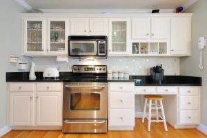 Admire the beauty of this small white kitchen adorned with a sleek black countertop that effortlessly complements the appliances. The white color scheme creates a sense of spaciousness and cleanliness, while the contrasting black countertop adds a touch of sophistication and modernity. The appliances seamlessly blend into the design, creating a cohesive and sleek aesthetic. Experience the perfect balance of elegance and functionality in this stylish kitchen, where the black countertop serves as a focal point, enhancing the overall visual appeal and creating a truly captivating culinary space.